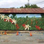 A pastoral mural featuring a coffee plant on a coffee barn in Carrboro N.C.